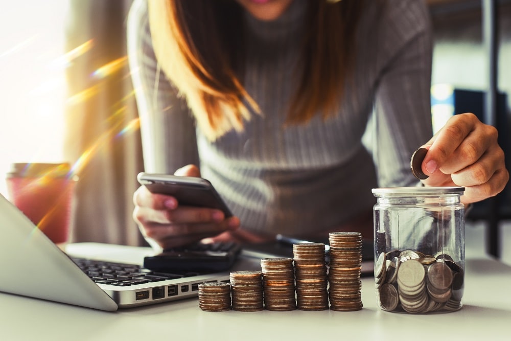 businesswoman-putting-coins-in-glass